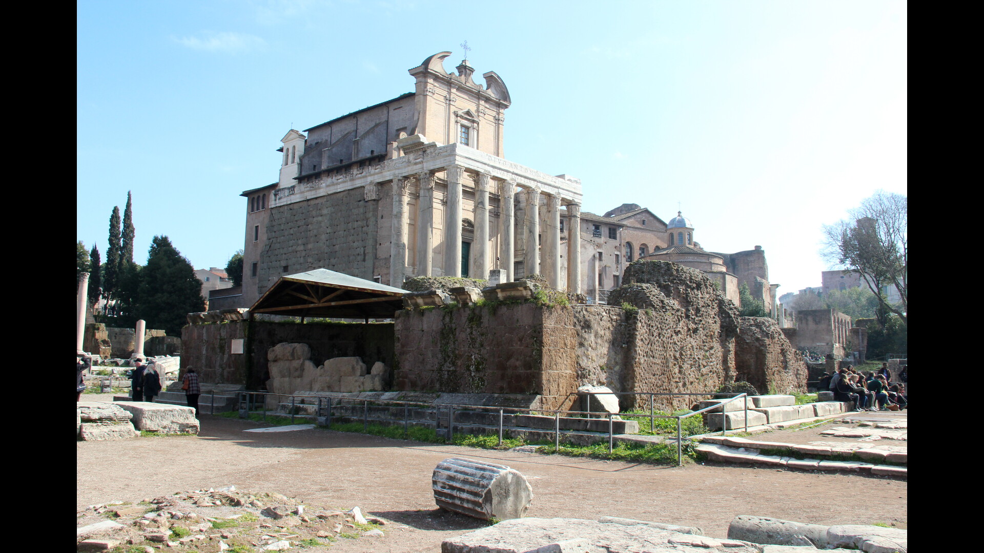 TempleCesarDivinise : Photo prise à Rome aujourd'hui. Vestiges du podium du temple de César divinisé avec le temple d’Antonin et Faustine en arrière-plan