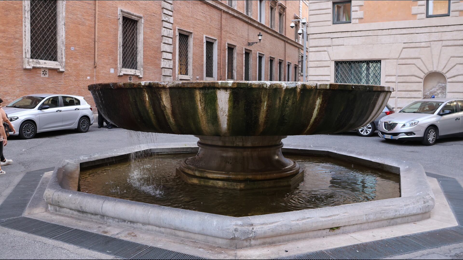 Une vasque large et profonde posée sur un socle circulaire, d'où s’écoule de l’eau dans un bassin inférieur octogonal.