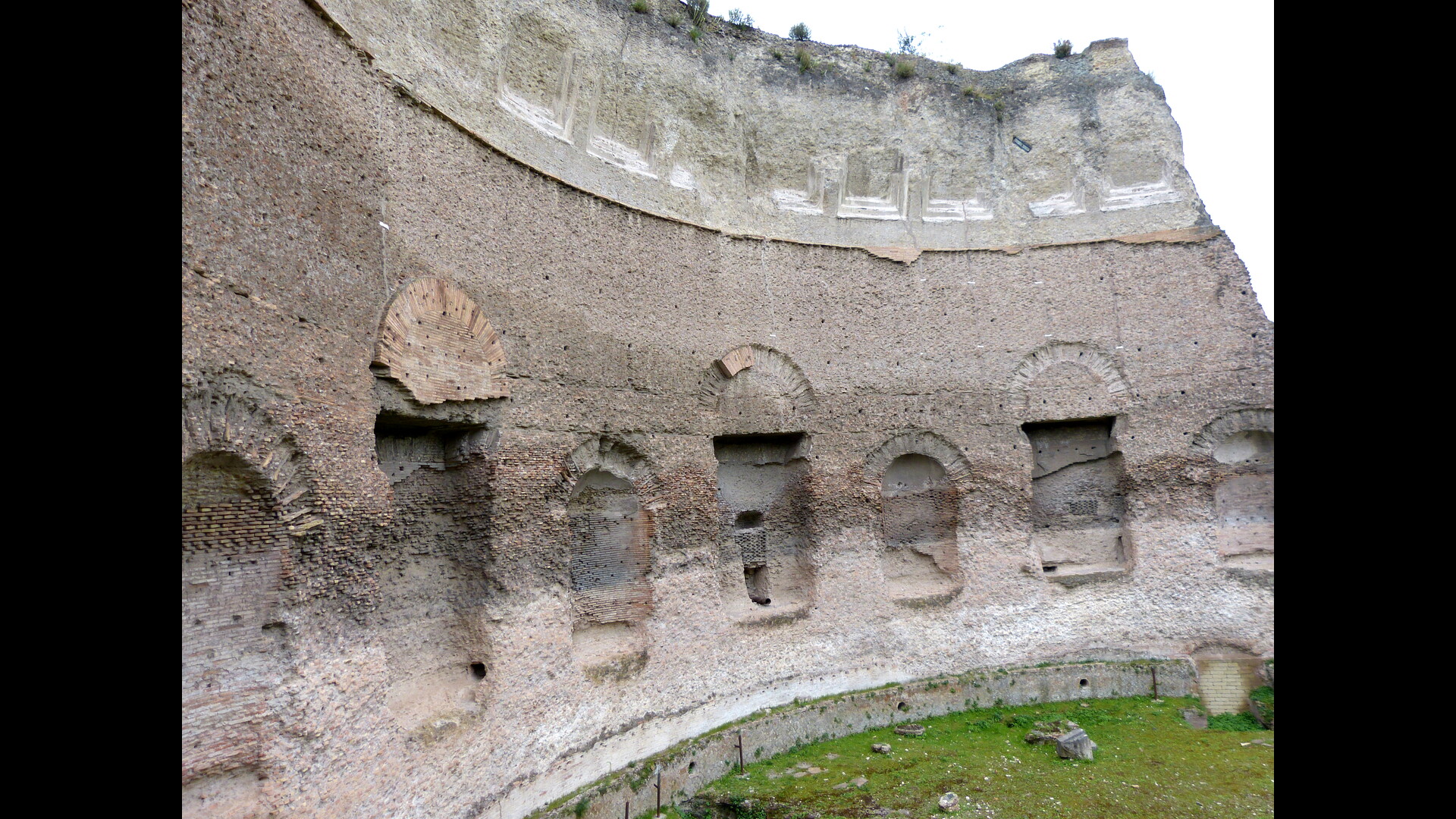 Un mur ancien en pierre et brique avec des ouvertures circulaires et des traces d'usure visible.
